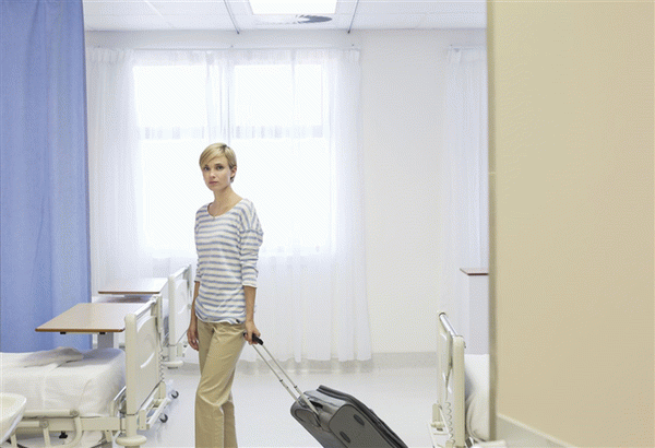 Patient with suitcase ready to leave hospital room